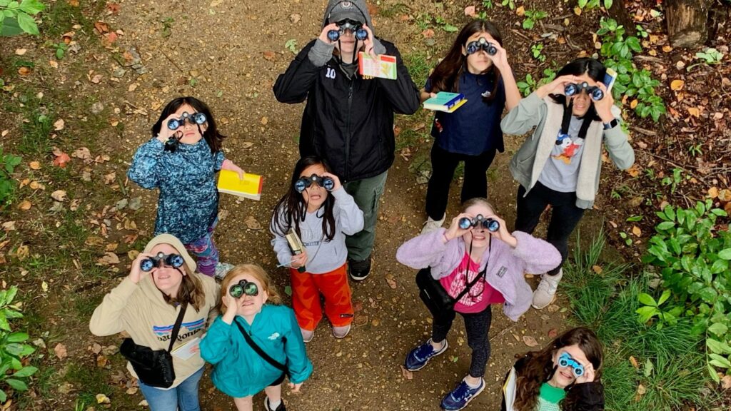 Children looking through binoculars during an outdoor nature program.
